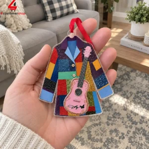 Hand holding a colorful quilt-patterned coat ornament with a pink acoustic guitar