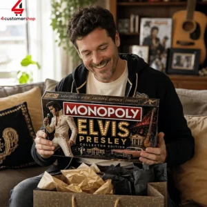 A man smiling while holding an Elvis Presley Collector Edition Monopoly board game box.